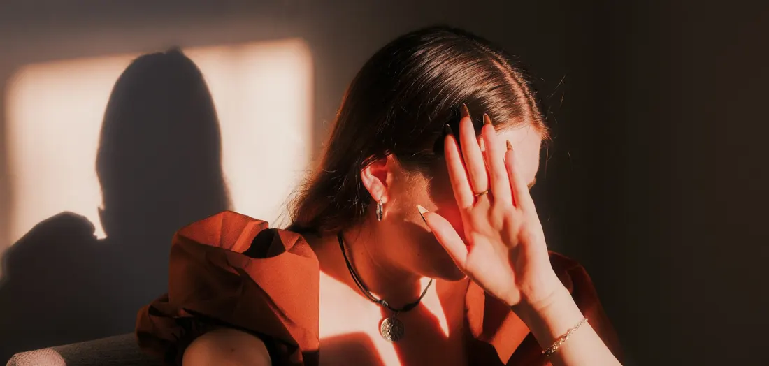 Mulher com as mãos no rosto, ansiosa